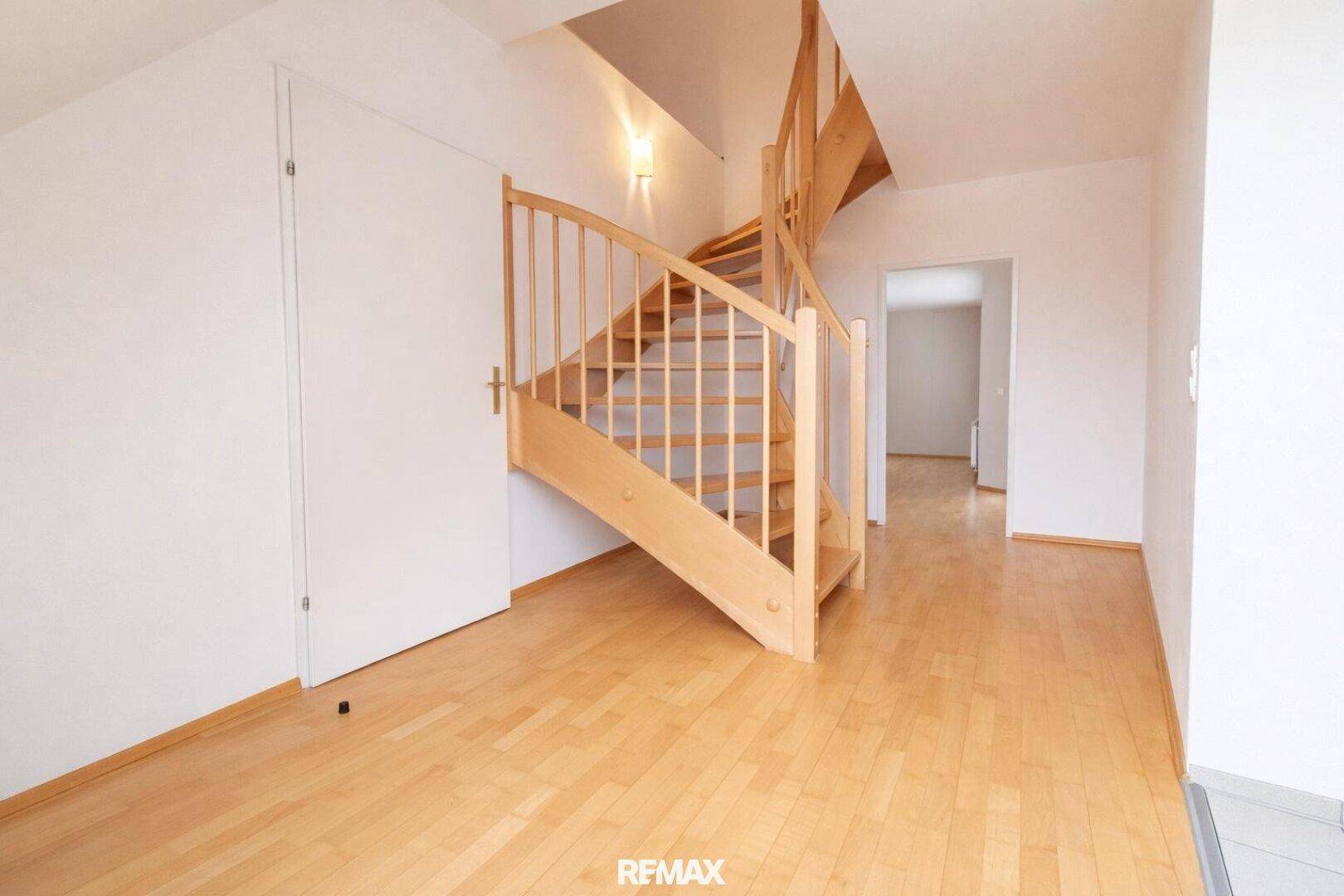 Heller Flur mit Holztreppe und Parkettboden, der die verschiedenen Ebenen verbindet.
