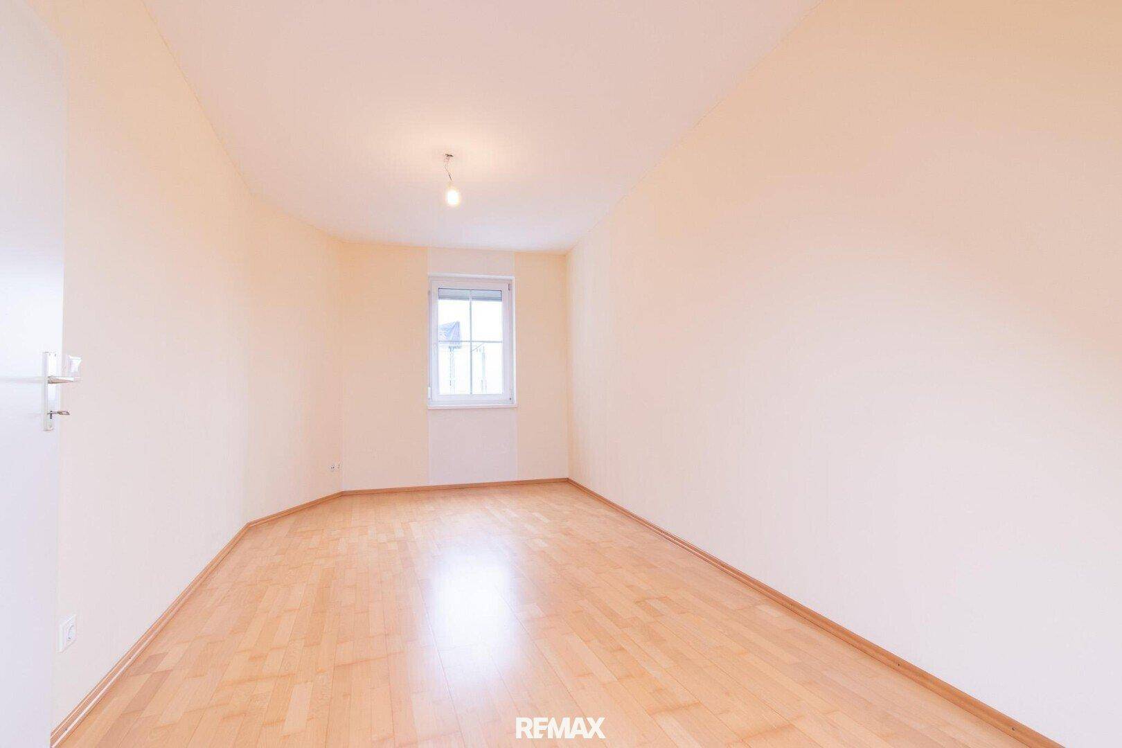 Leeres Schlafzimmer mit hellem Parkettboden und Fenster, bereit zur individuellen Gestaltung.