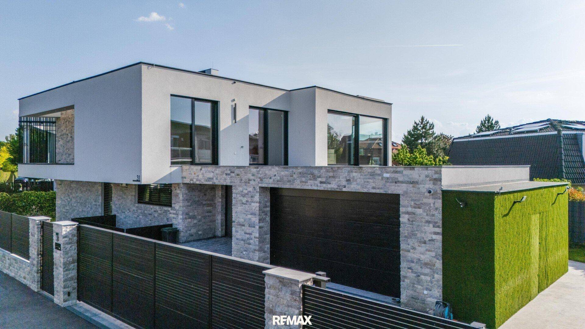 Moderne Villa mit weißer Fassade, Steinelementen und integrierter Doppelgarage.