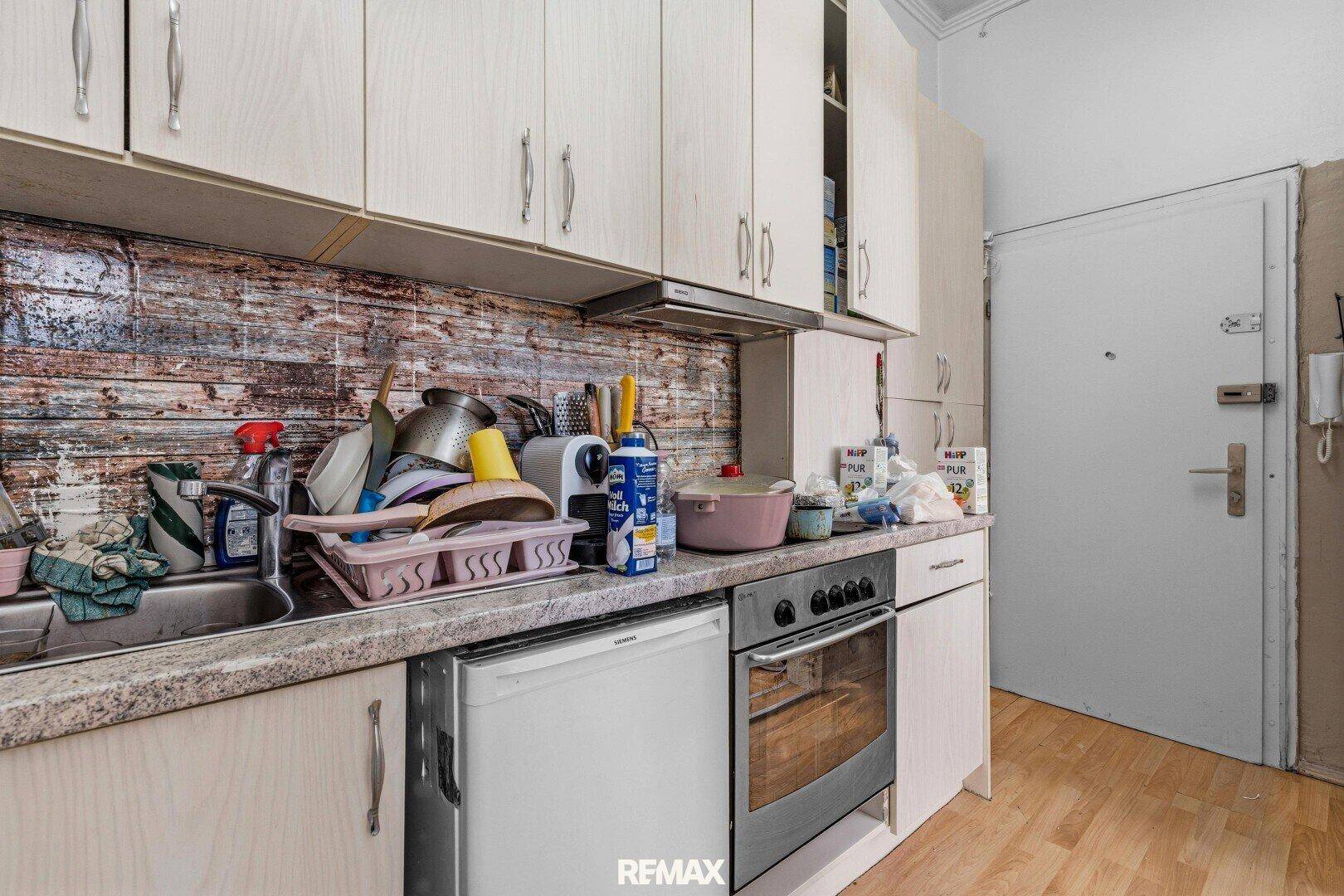 Küche mit Spüle, Herd, kleinem Kühlschrank und Oberschränken.