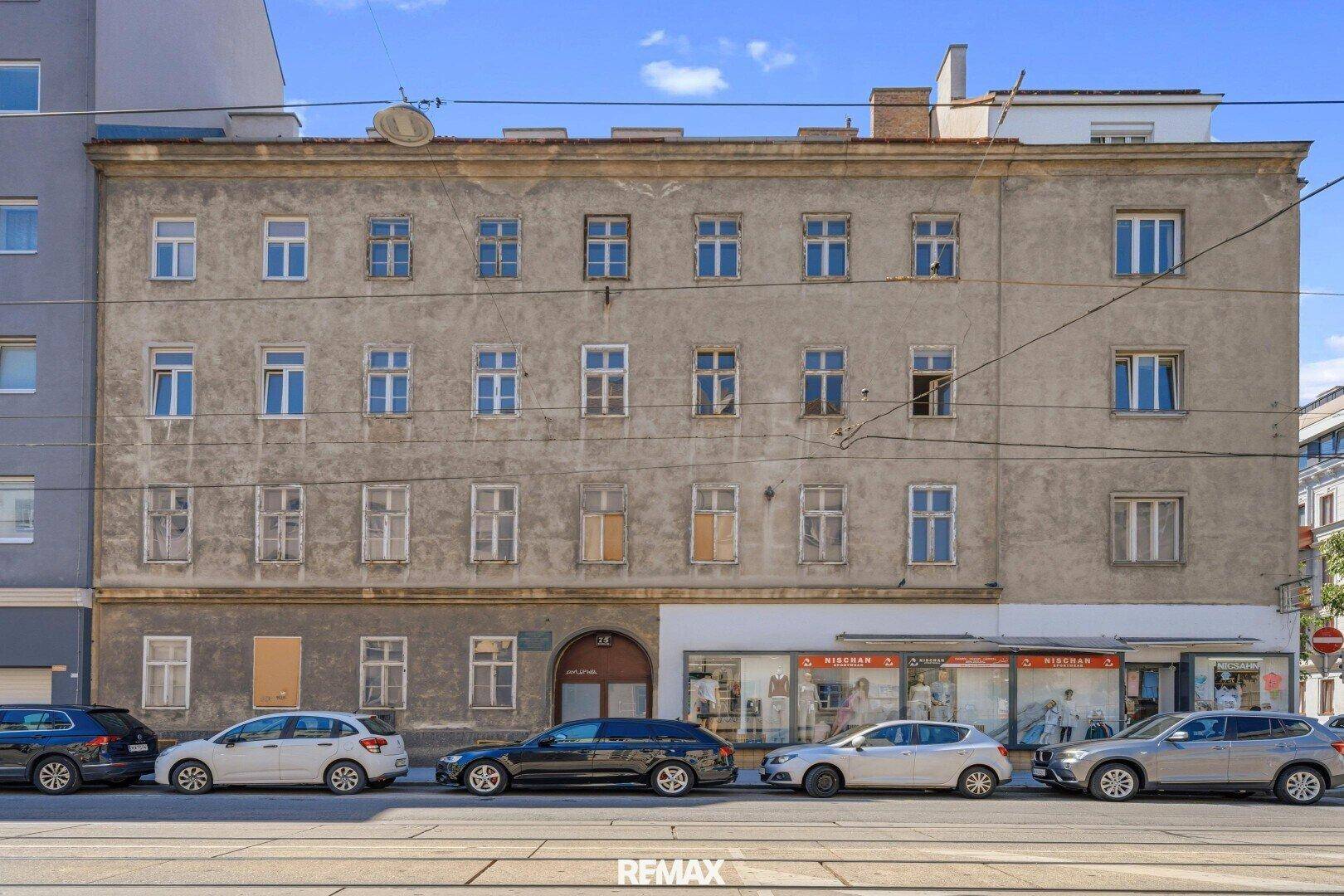 Fassade eines alten Wohngebäudes an einer Straße mit Geschäften im Erdgeschoss.