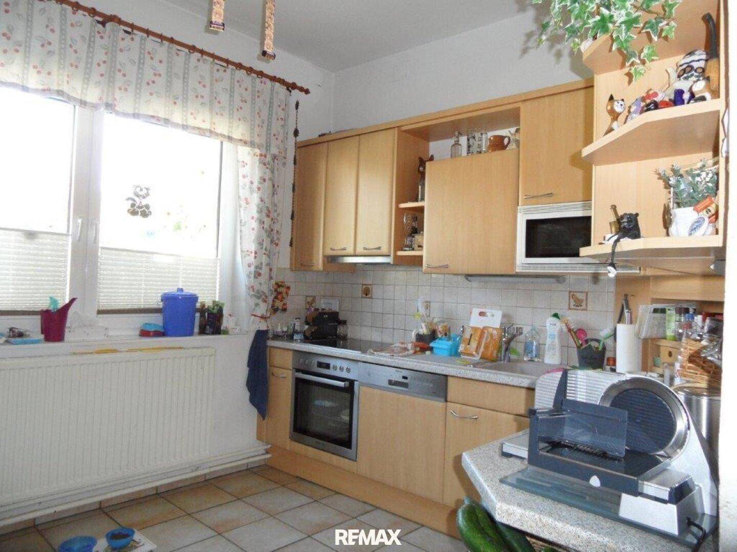 Funktionale Küche mit Holzschränken, Fliesenrückwand und integrierten Geräten.