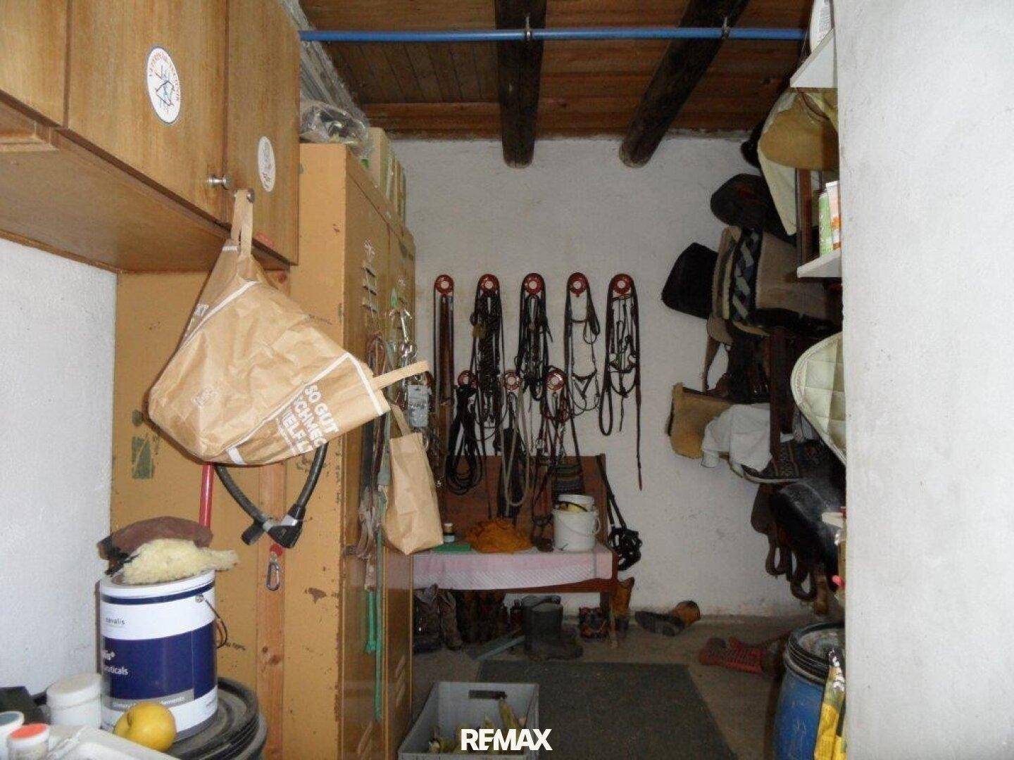 Geräteraum mit Holzdecke, gefüllt mit Pferdegeschirr, Sätteln und verschiedenen Utensilien.
