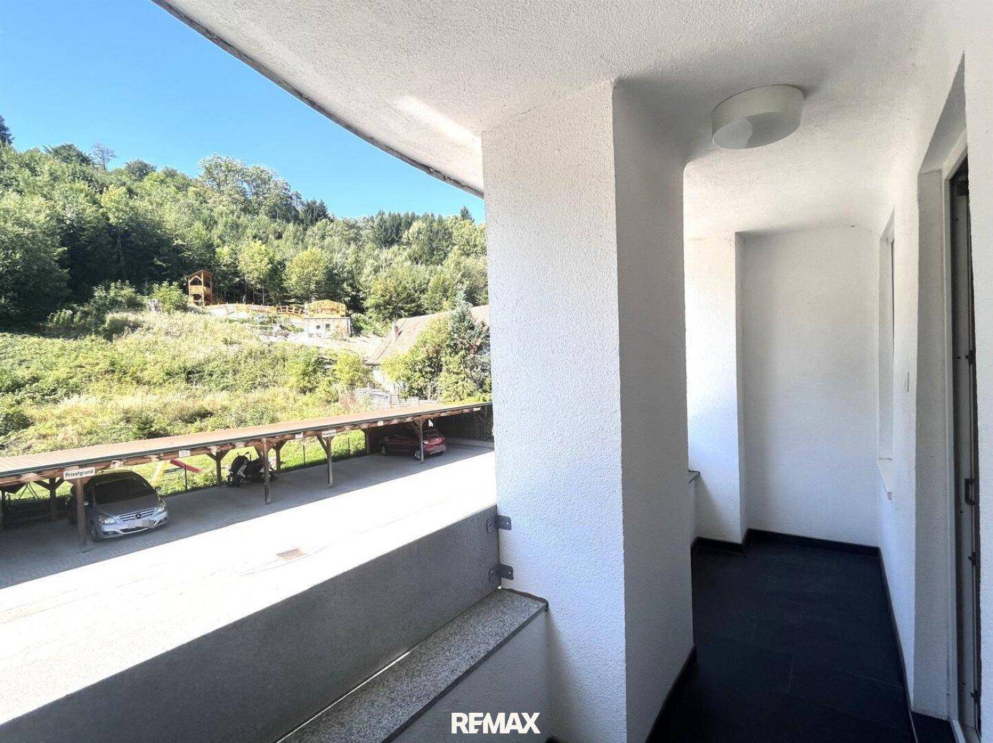 Schmaler Balkon mit Blick auf die umliegende Hügellandschaft und einen Carport.