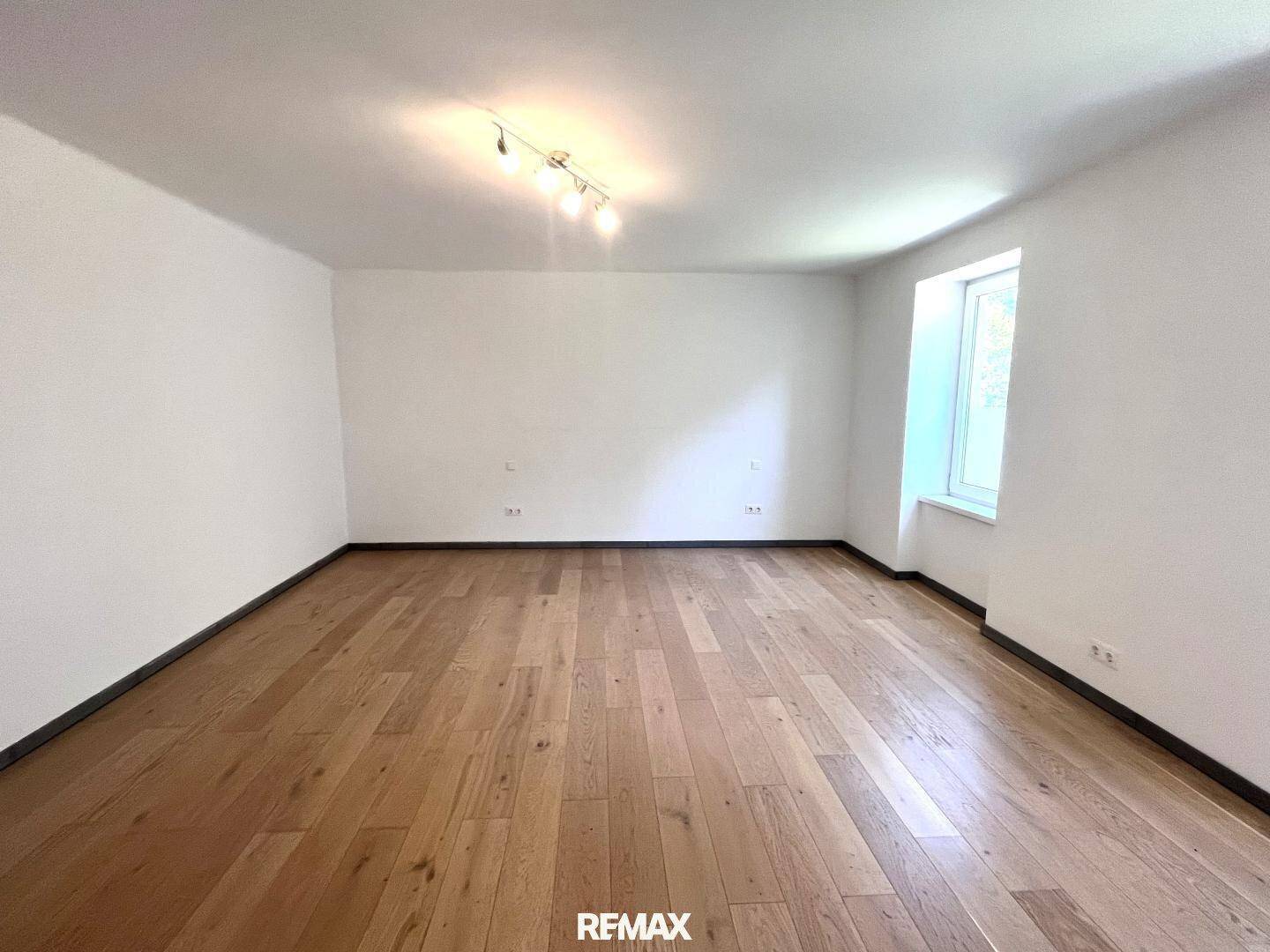 Ruhiges Zimmer mit Holzboden und einem Fenster, das viel Tageslicht hereinlässt.