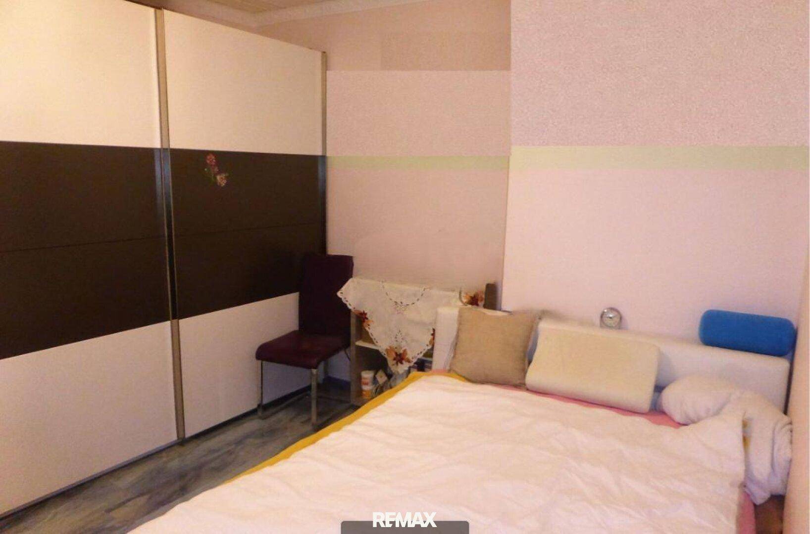 Schlafzimmer mit großem Schiebetürenschrank und einem Bett mit hellen Kissen.