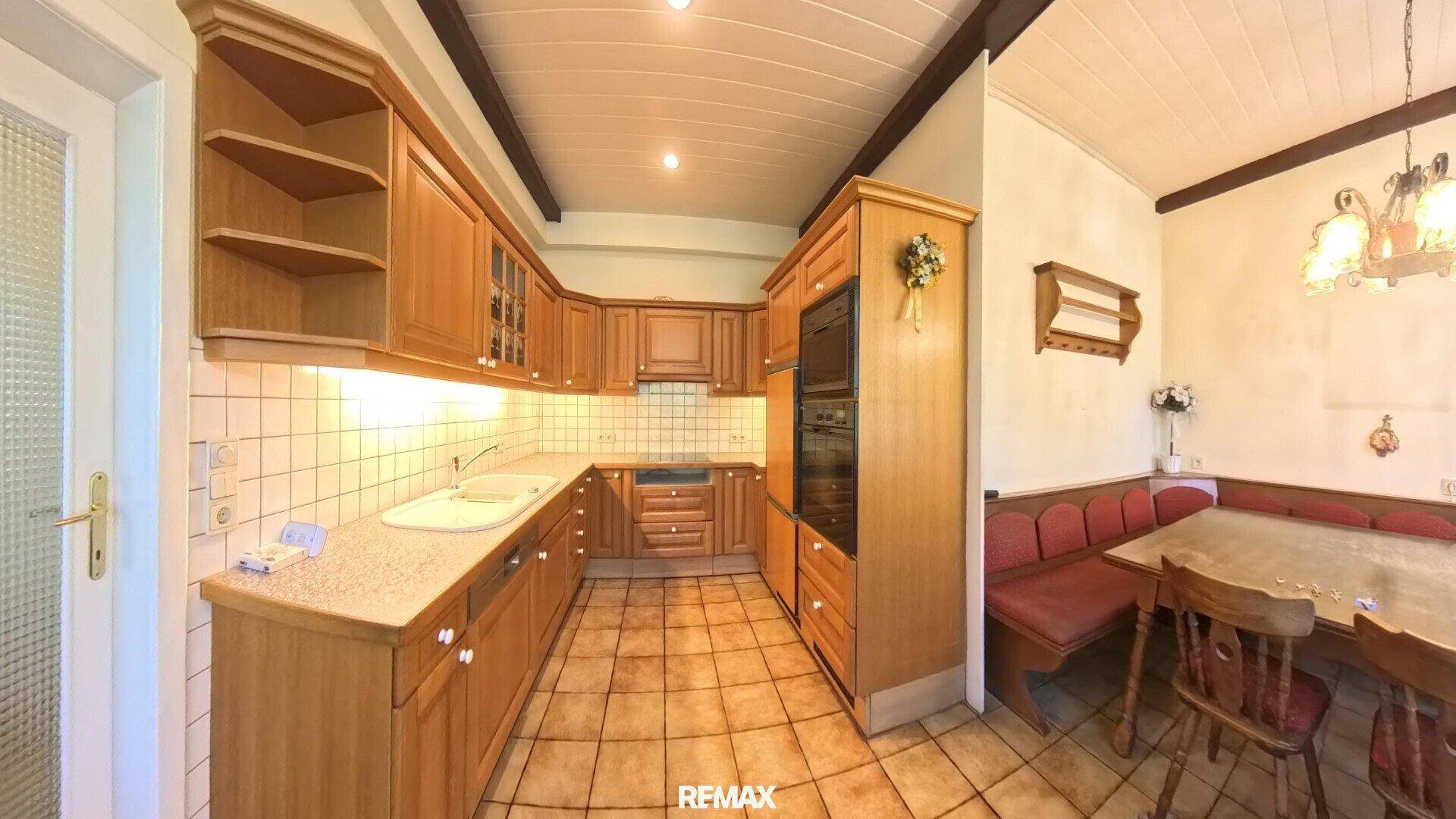 Traditionelle Holzküche mit Einbaugeräten, gefliestem Boden und einer gemütlichen Essecke mit Eckbank.