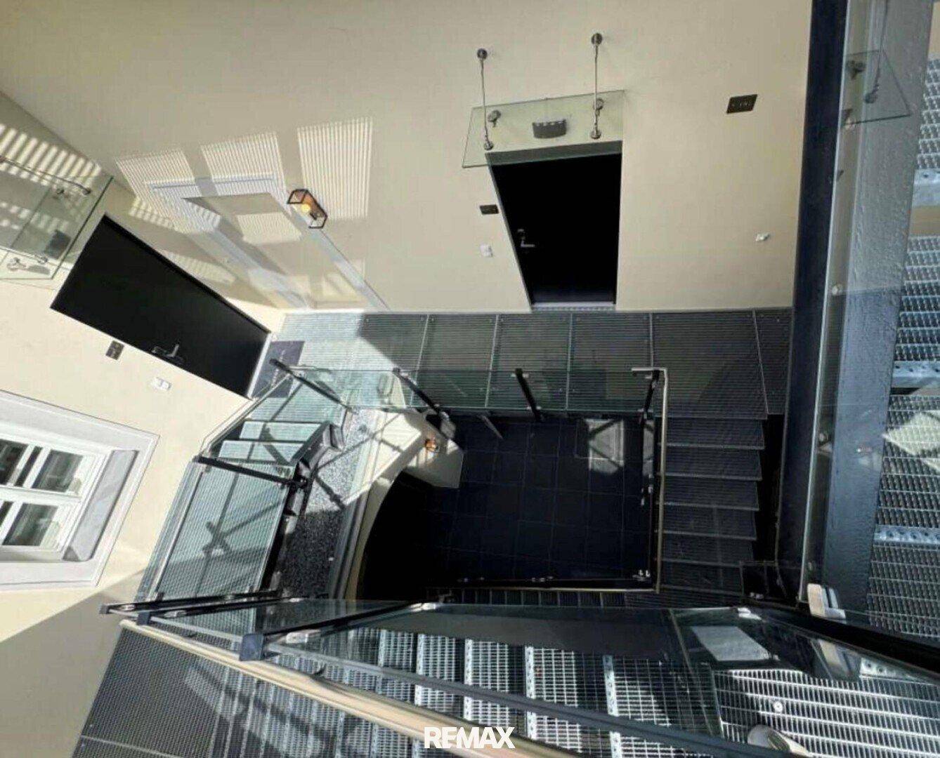 Blick von oben auf das Treppenhaus mit Glasgeländer und modernen Oberlichtern.