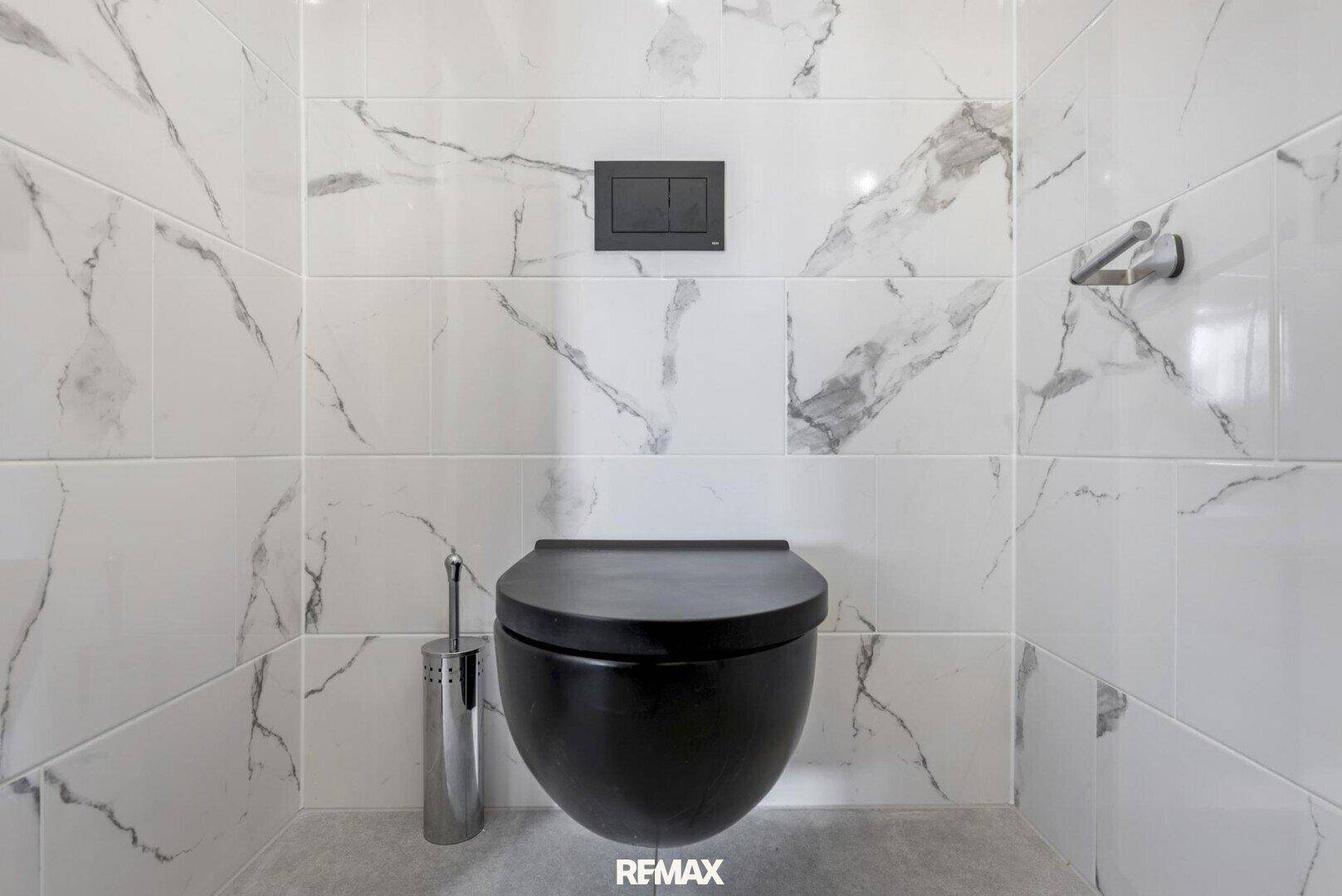 Separate Toilette mit Wand-WC und eleganten Marmor-Effekt-Fliesen.