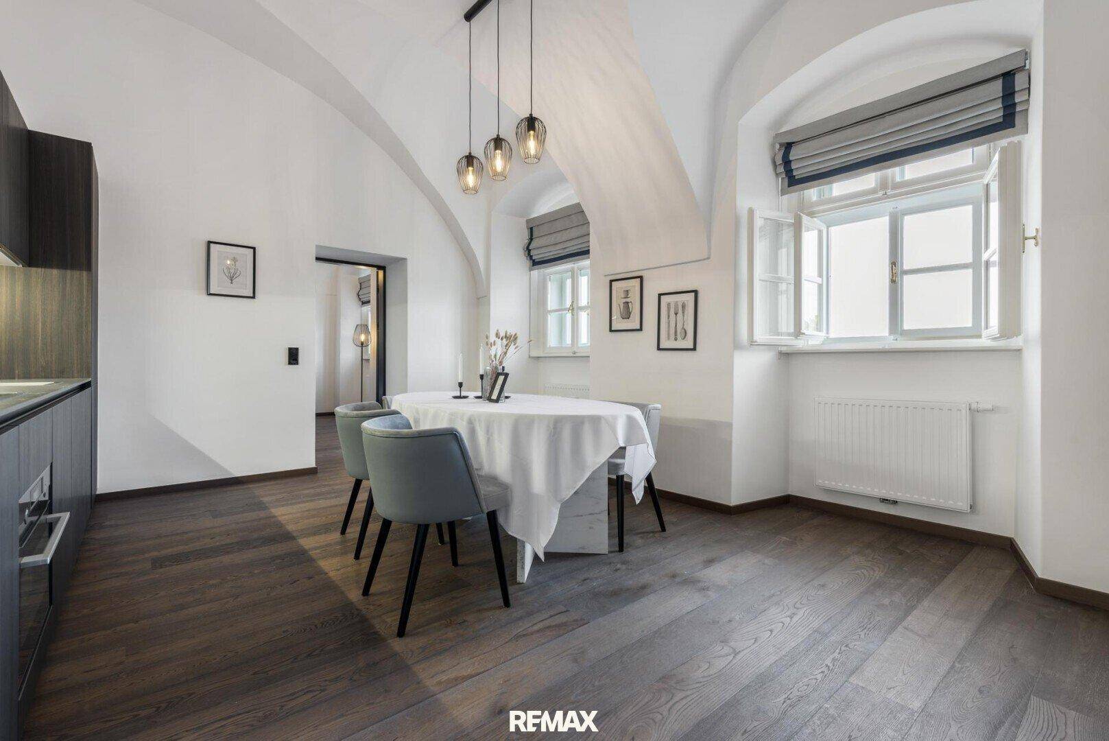 Heller Essbereich mit Holzboden, gewölbter Decke und Fenstern mit eleganten Rollos.