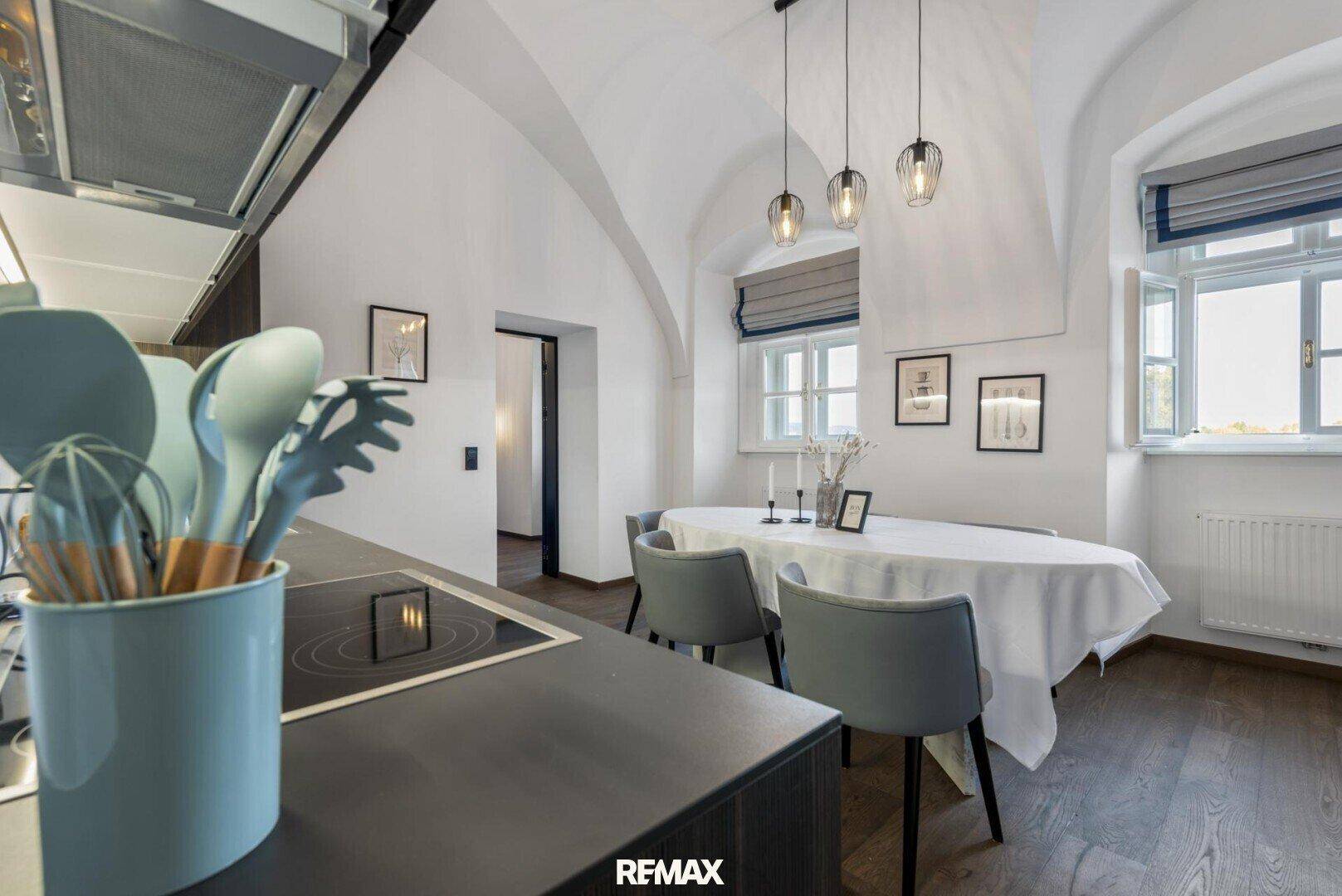 Offene Küche mit Induktionskochfeld und Essbereich mit gewölbter Decke und Holzboden.