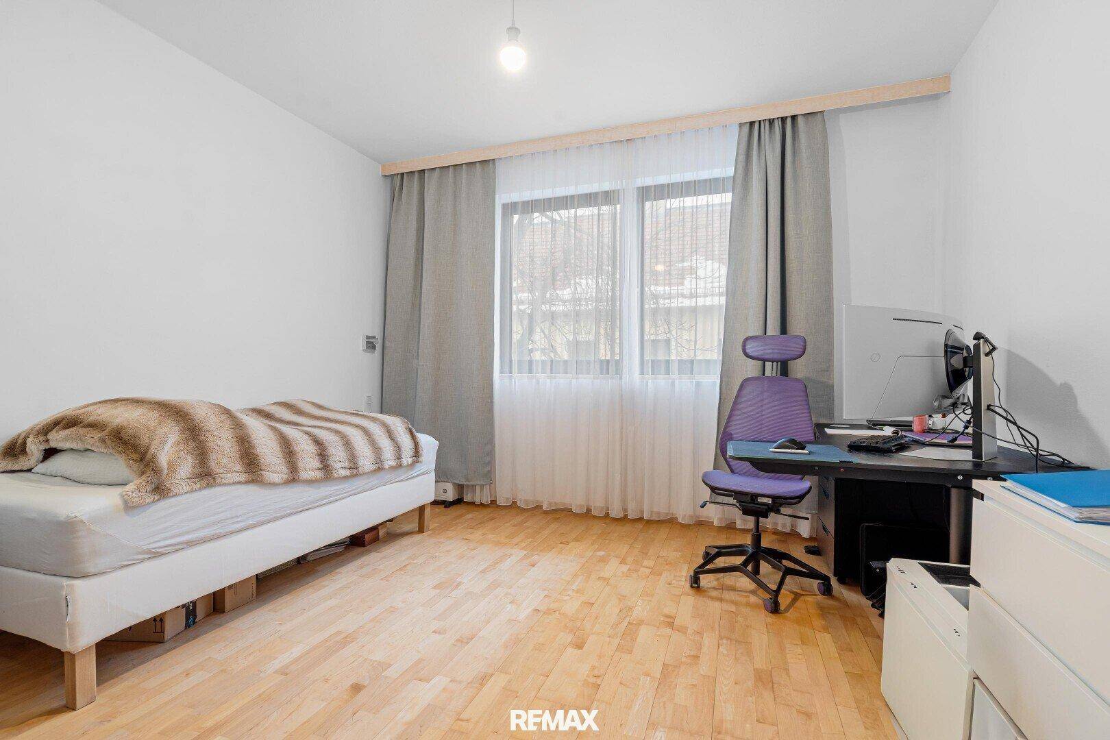 Schlafzimmer mit Holzboden, Einzelbett und Schreibtisch, hell und einfach eingerichtet.