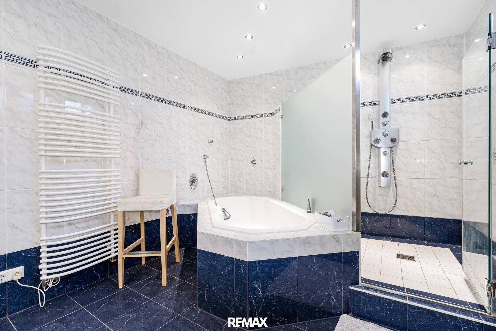 Geräumiges Badezimmer mit Eckbadewanne, Duschbereich und blauen Fliesen.