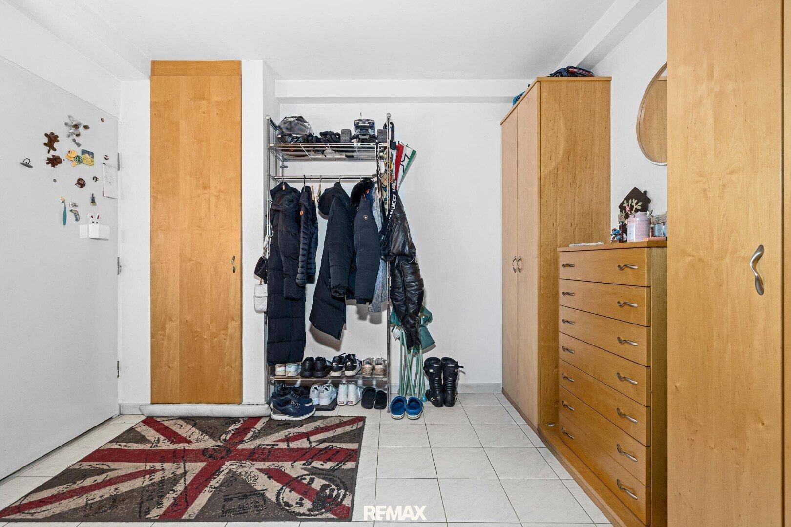 Eingangsbereich mit Fliesenboden, Garderobe und Holzschränken, funktional eingerichtet.