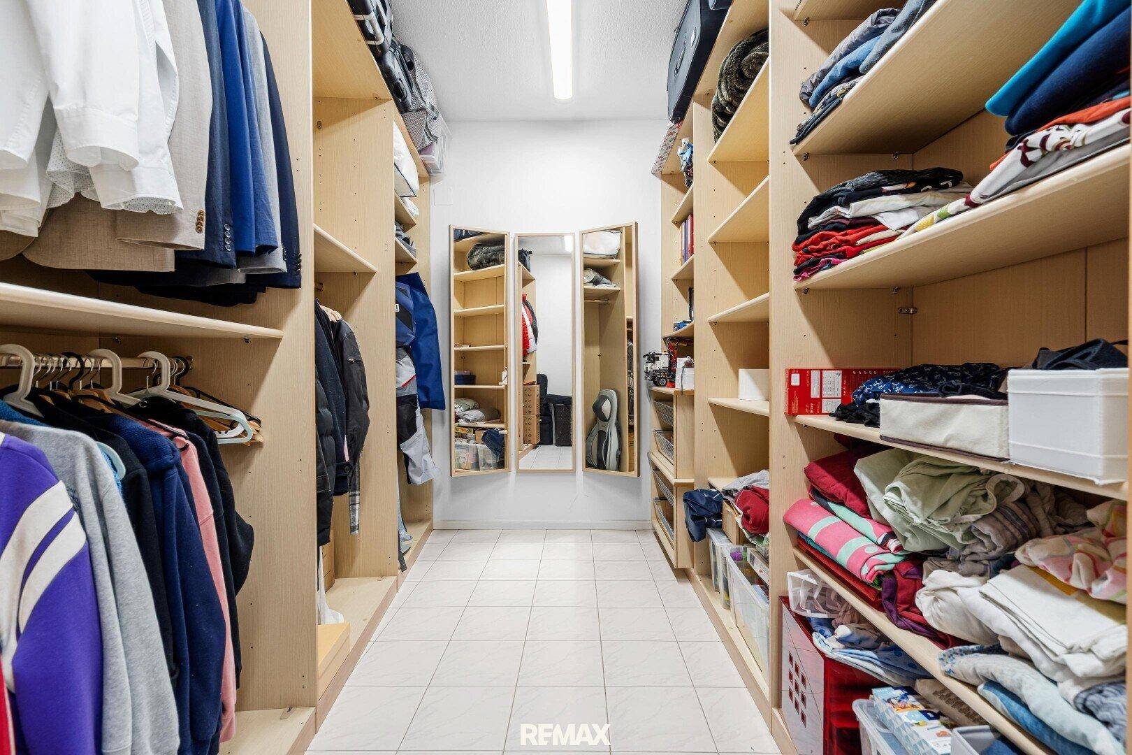 Begehbarer Kleiderschrank mit vielen Regalen und Spiegeln, gut organisiert.
