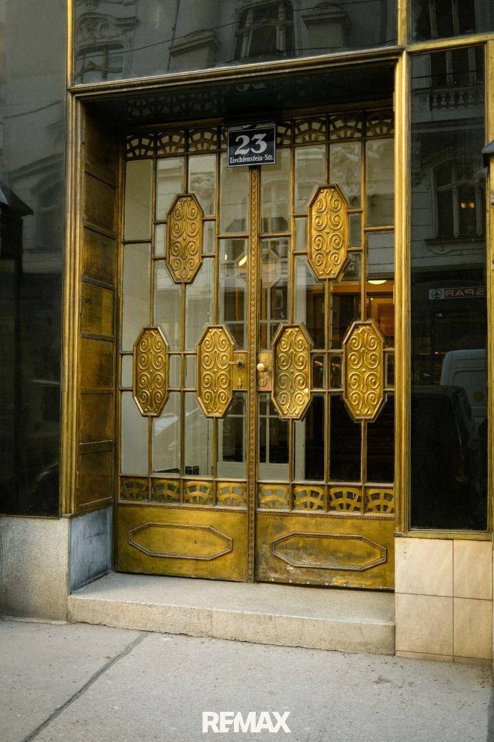 Prunkvolles goldenes Eingangsportal eines historischen Gebäudes mit kunstvollen Verzierungen.