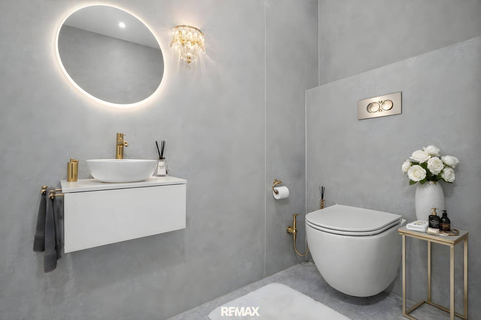 Elegantes Gäste-WC mit schwebendem Waschtisch, beleuchtetem Spiegel und goldenen Akzenten.