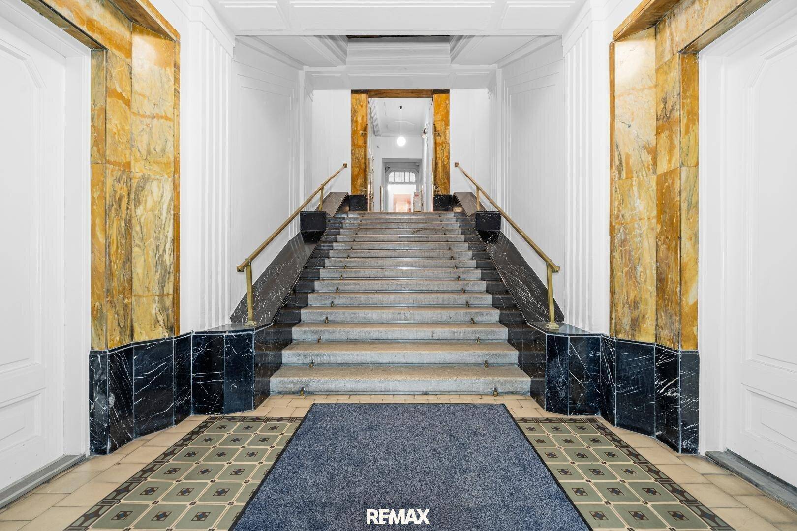 Repräsentativer Eingangsbereich mit breiter Marmortreppe und eleganten Fliesenböden.