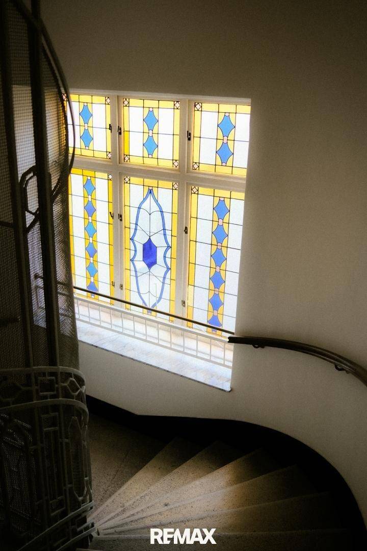 Historisches Treppenhaus mit kunstvollem Buntglasfenster, das natürliches Licht hereinlässt.