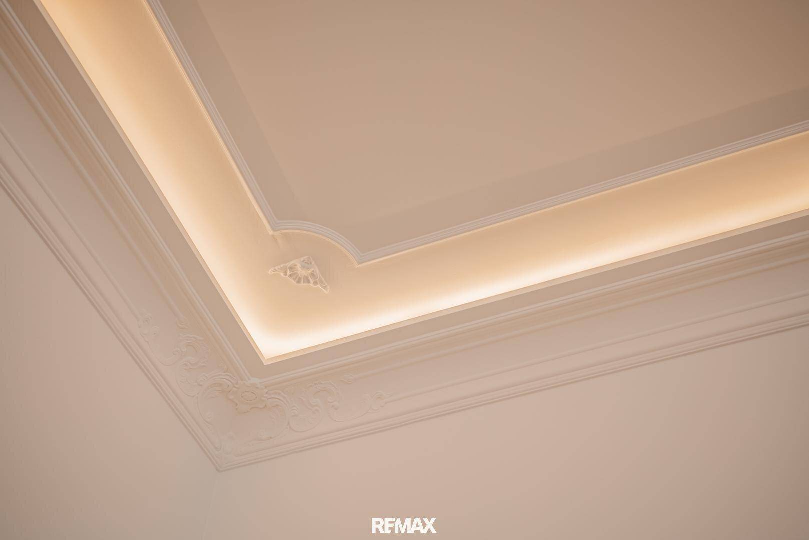Elegante Stuckdecke mit indirekter Beleuchtung und feinen Zierleisten im Detail.
