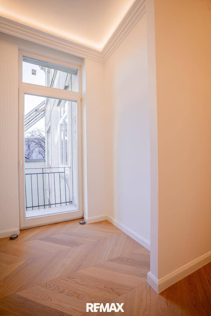 Heller Raum mit Fischgrätparkett und französischem Balkon für viel Tageslicht.