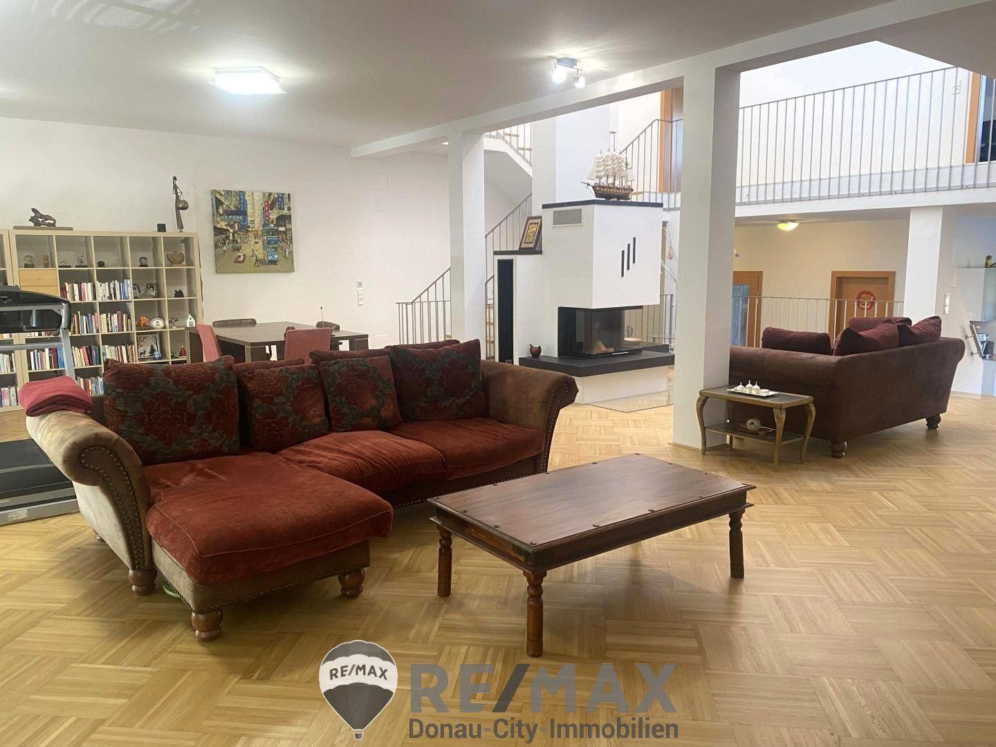 Geräumiges Wohnzimmer mit Parkettboden, gemütlichen Sofas und einem modernen Kamin.