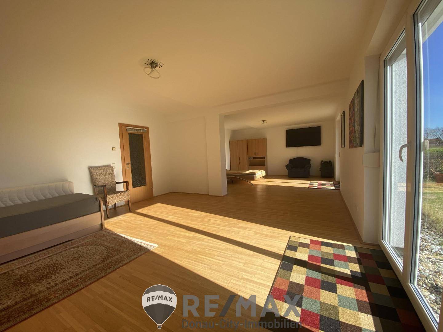 Helles, offenes Wohnzimmer mit Parkettboden und Zugang zur Terrasse, ideal für gesellige Stunden.