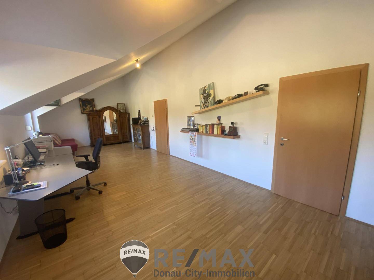 Geräumiges Arbeitszimmer mit Parkettboden, Dachschrägen und viel Tageslicht.
