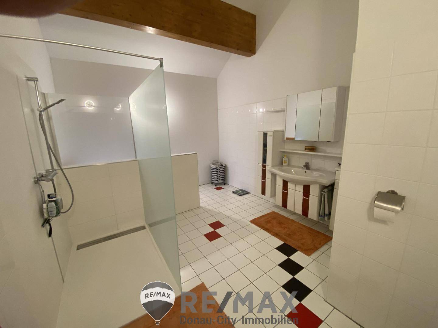 Helles Badezimmer mit begehbarer Dusche, weißen Fliesen und Dachschräge.