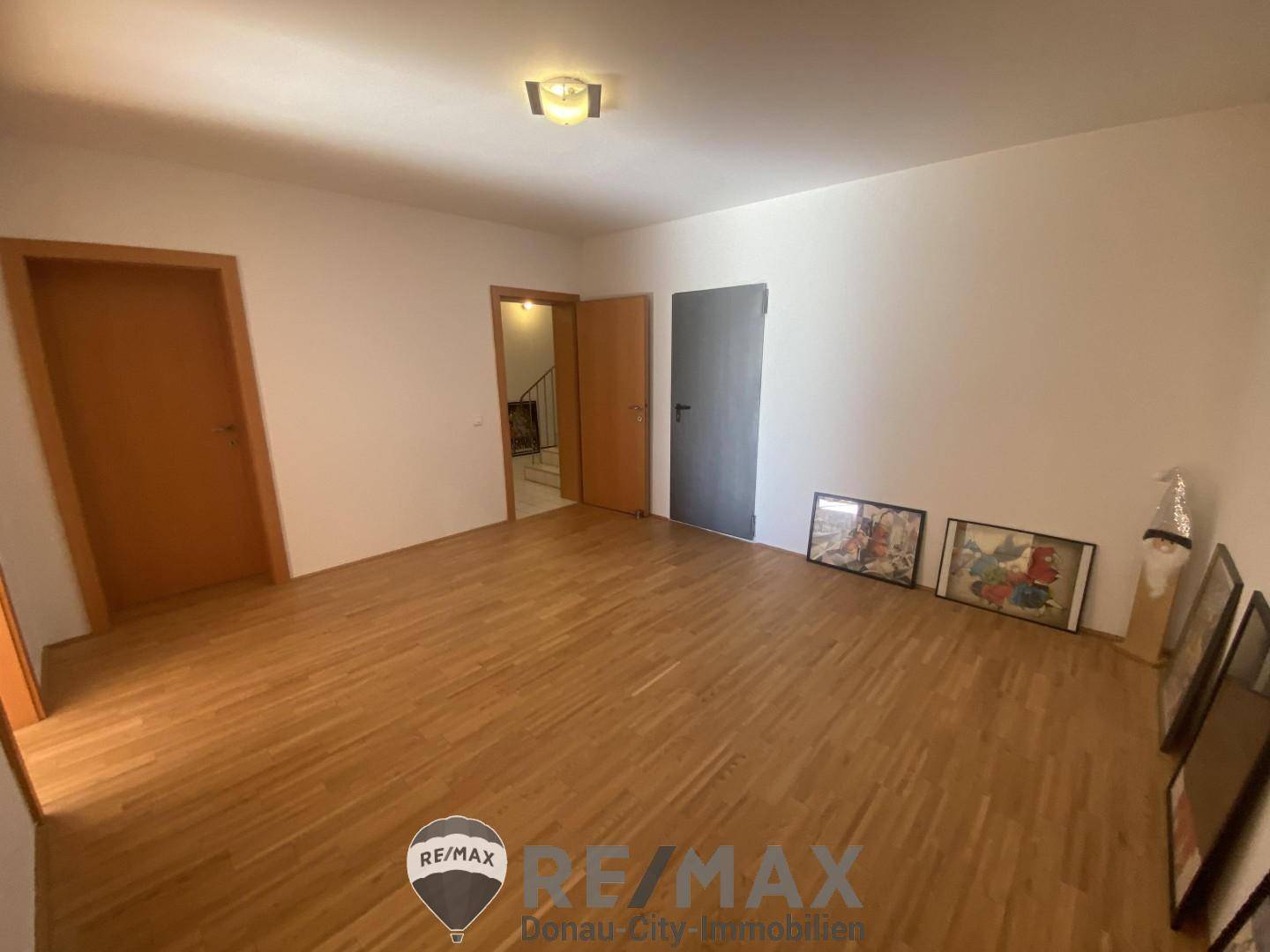 Geräumiges Zimmer mit Parkettboden und mehreren Türen, vielseitig nutzbar.