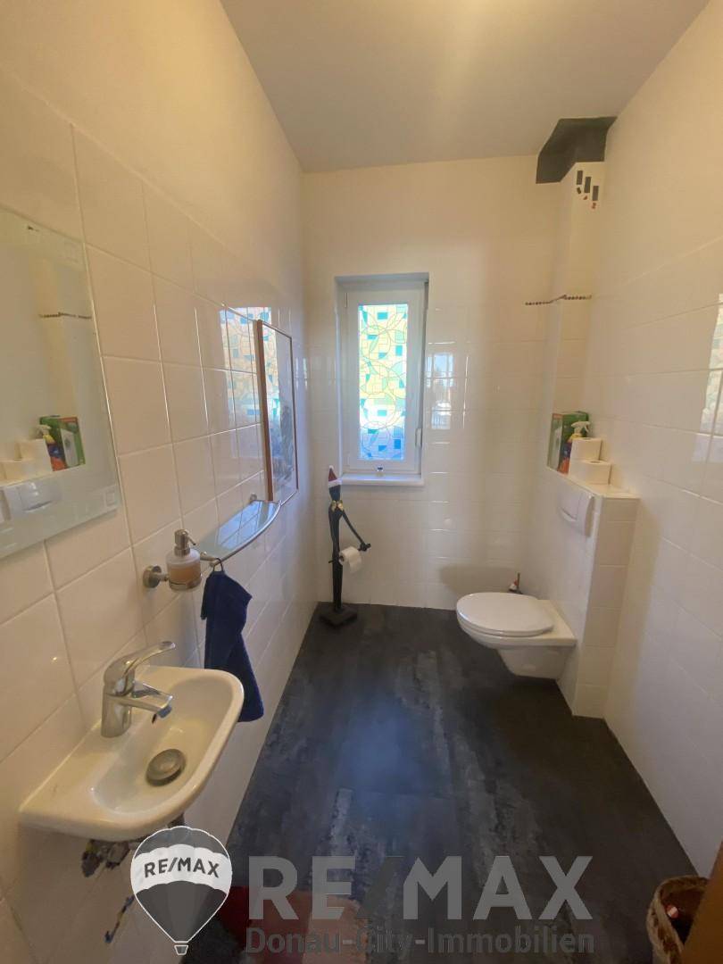 Kleines Gäste-WC mit weißen Fliesen, Fenster und modernem Waschbecken.