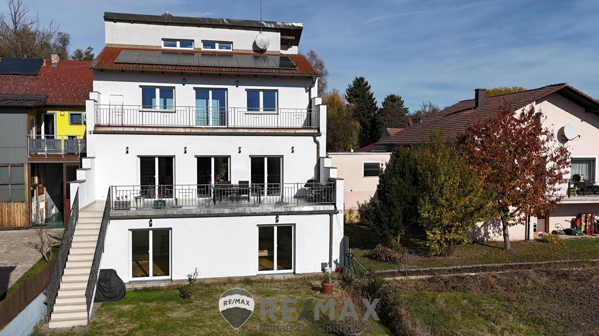 Modernes Mehrfamilienhaus mit mehreren Balkonen und Photovoltaikanlage auf dem Dach, zeitgemäße Architektur.