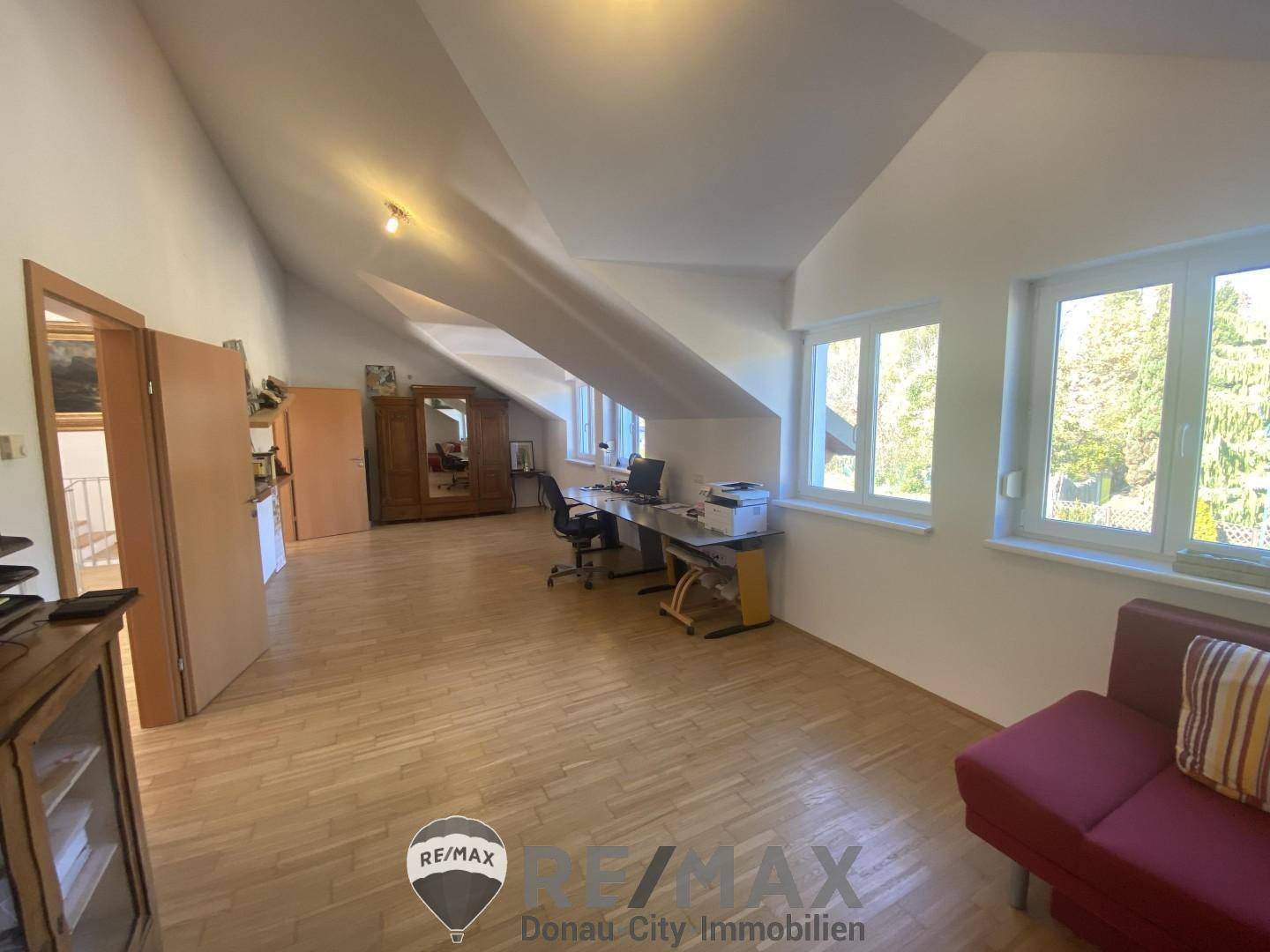 Helles Arbeitszimmer mit Parkettboden, großen Fenstern und schrägen Decken.