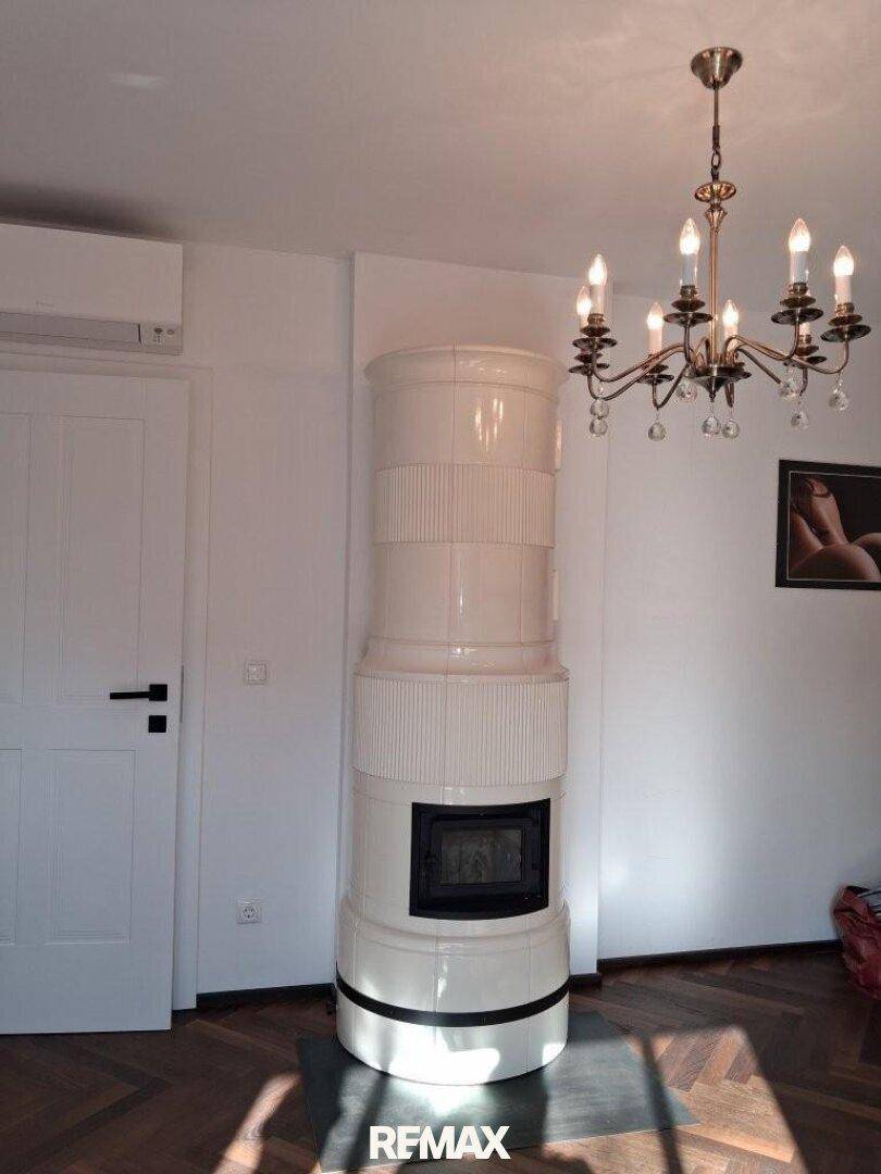 Gemütlicher Raum mit traditionellem Kachelofen, Holzboden und Kronleuchter.
