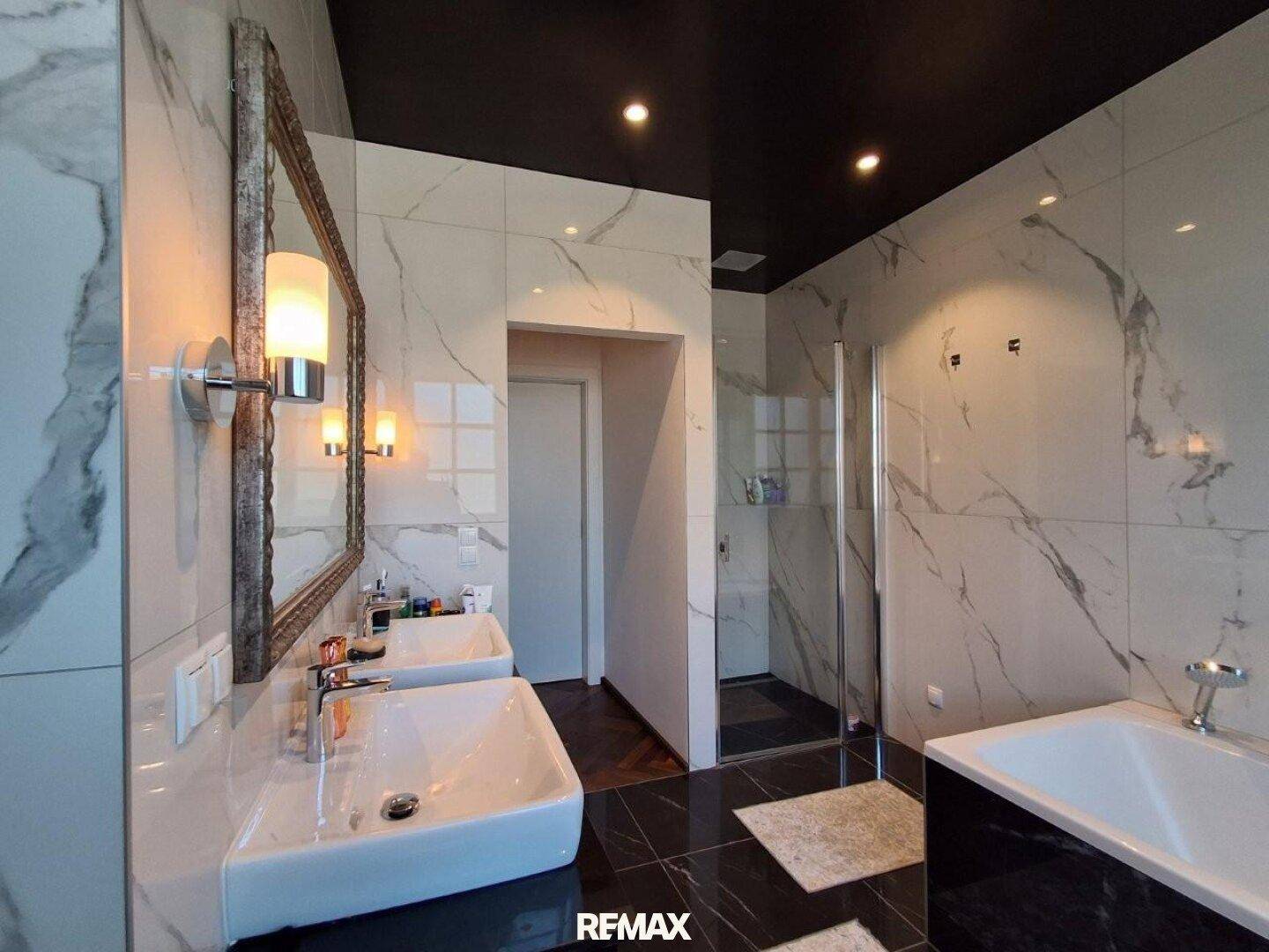 Elegantes Badezimmer mit Marmorfliesen, Doppelwaschbecken und begehbarer Dusche.