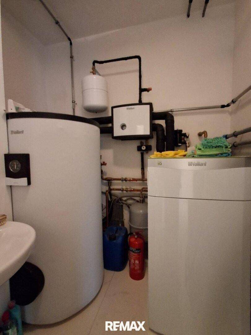Raum mit Heizungsanlage, Warmwasserspeicher und sichtbaren Rohrleitungen für die Haustechnik.