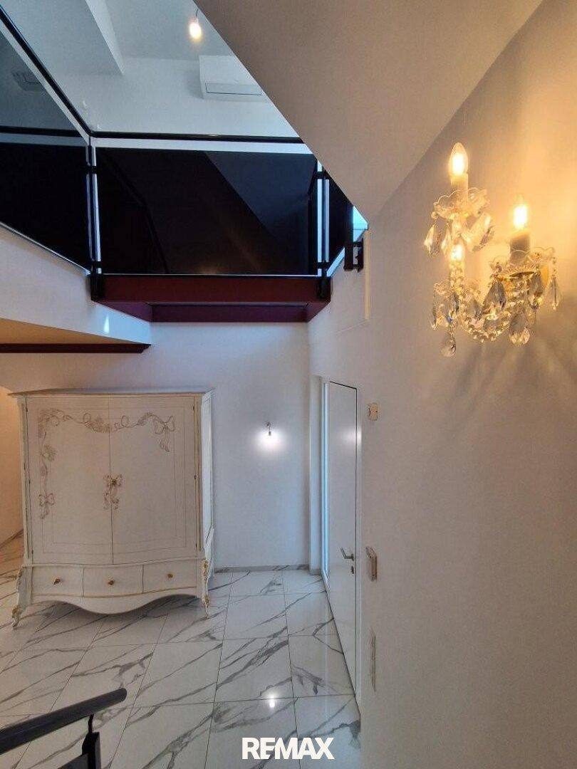 Heller Flur mit Marmorfliesen, elegantem Schrank und Blick auf die obere Etage.