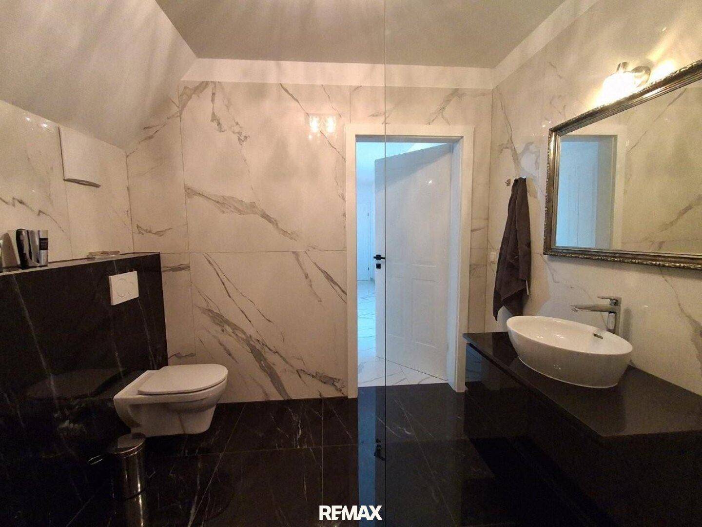 Modernes Badezimmer mit Marmorfliesen, wandhängendem WC und elegantem Waschbecken.