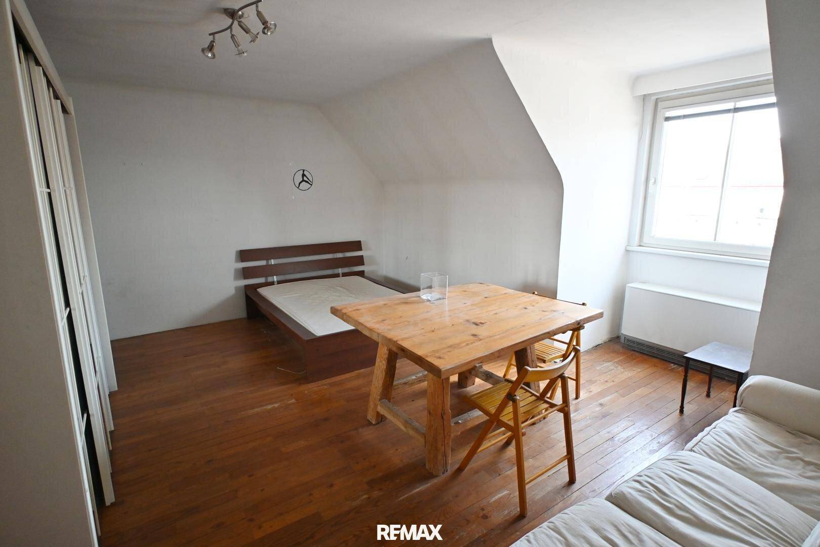 Gemütliches Schlafzimmer mit Holzboden, Dachschräge und Fenster, bietet eine helle und ruhige Atmosphäre.