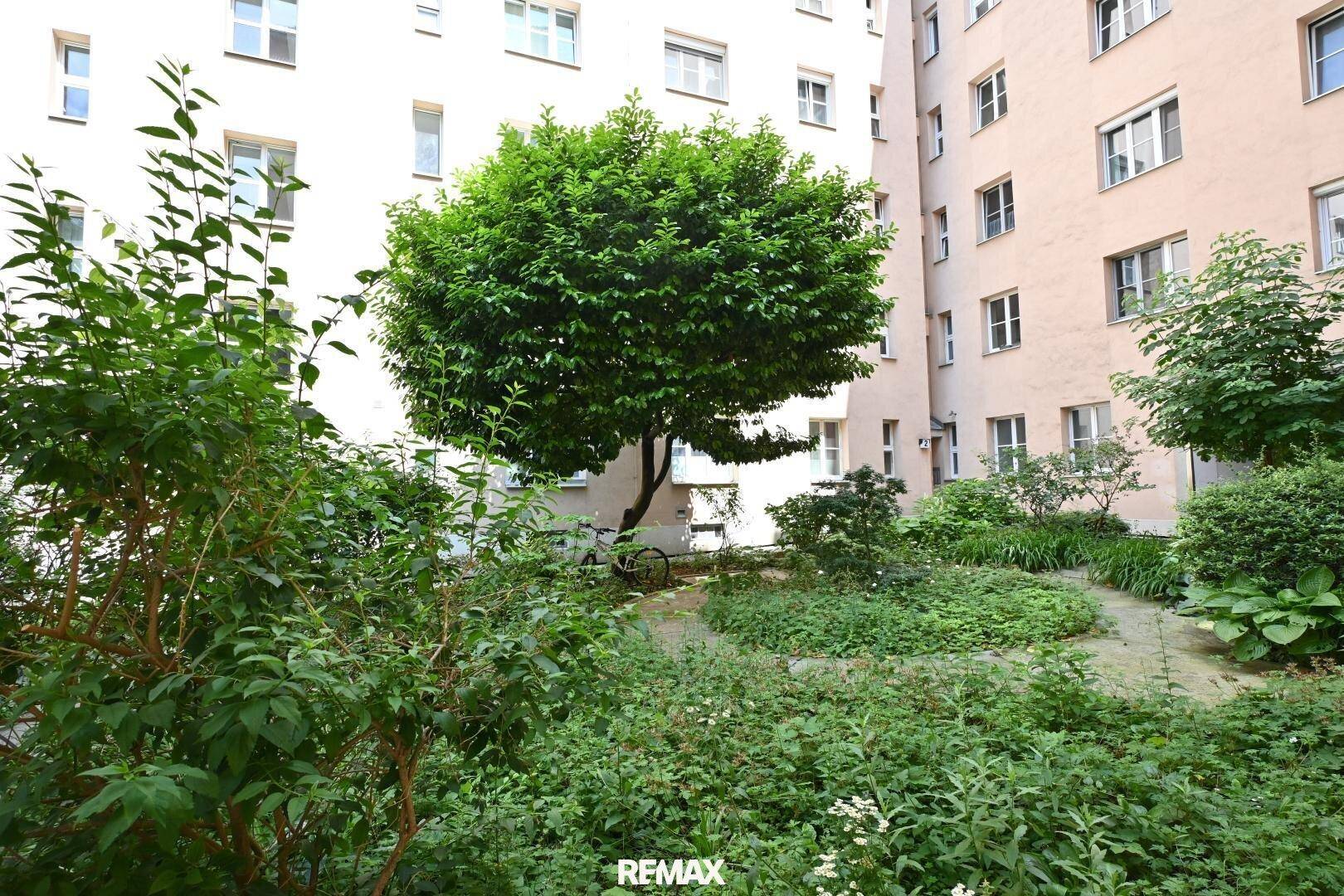 Ruhiger Innenhofgarten mit üppiger Vegetation und Bäumen, schafft eine entspannende Atmosphäre.