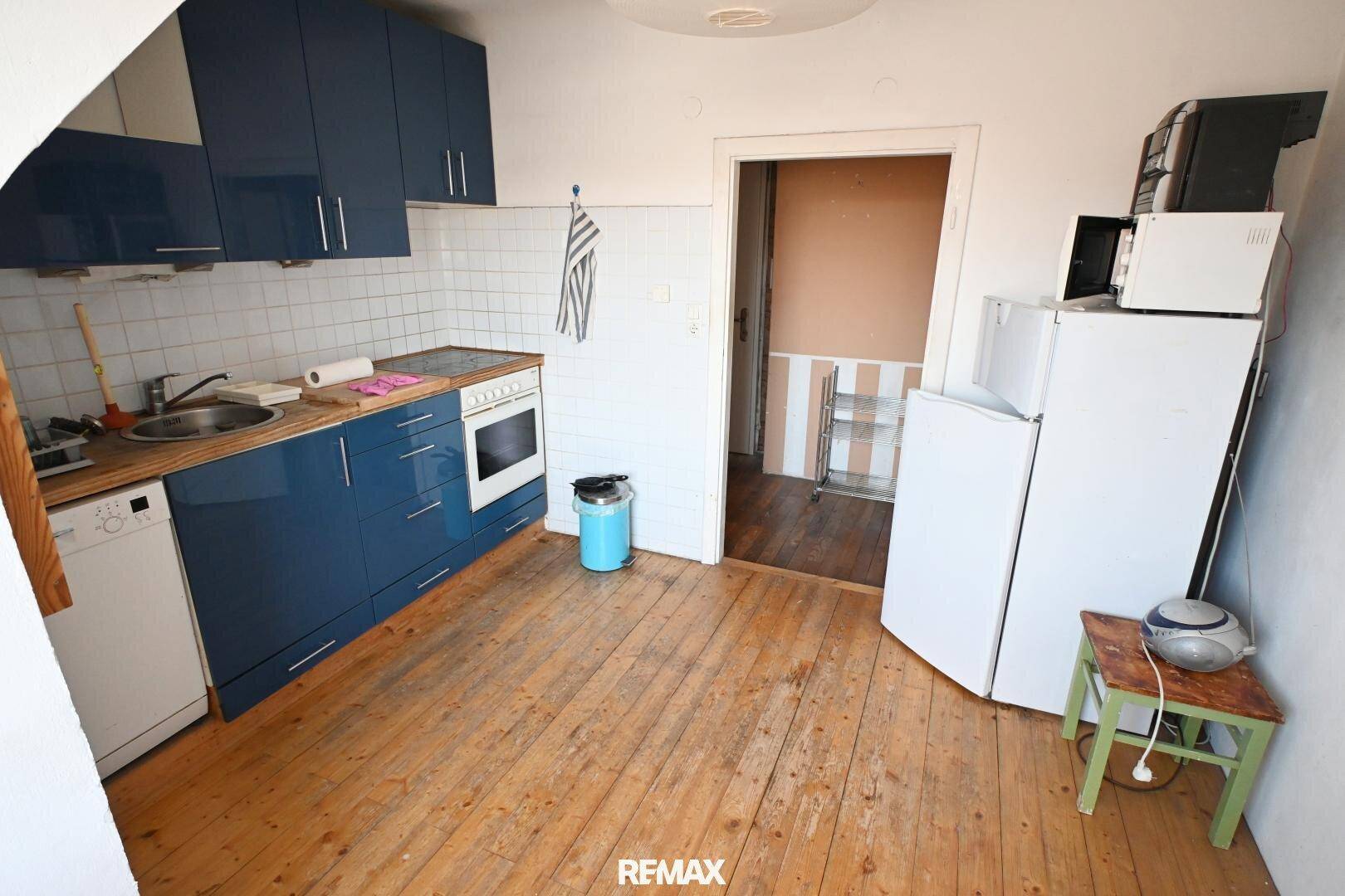 Praktische Küche mit blauen Fronten, Holzdielenboden und Geräten, ideal für den täglichen Gebrauch.