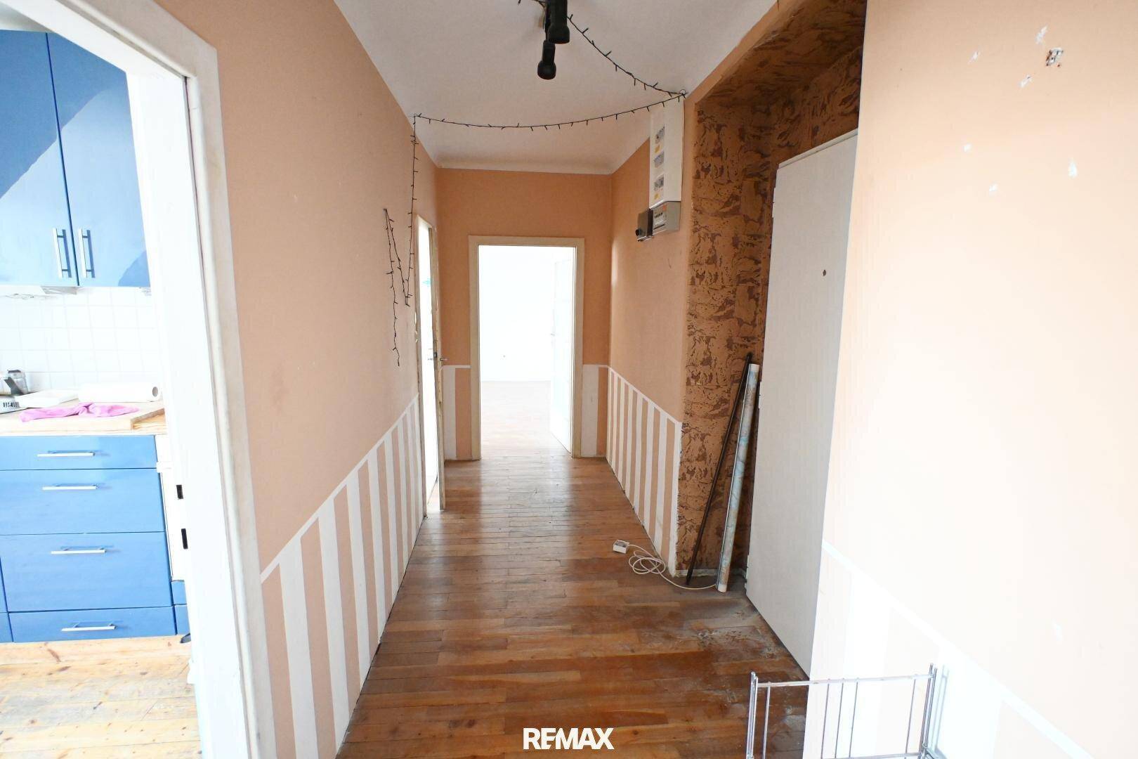 Heller Flur mit Holzboden und farbigen Wänden, bietet Zugang zu den verschiedenen Bereichen der Wohnung.