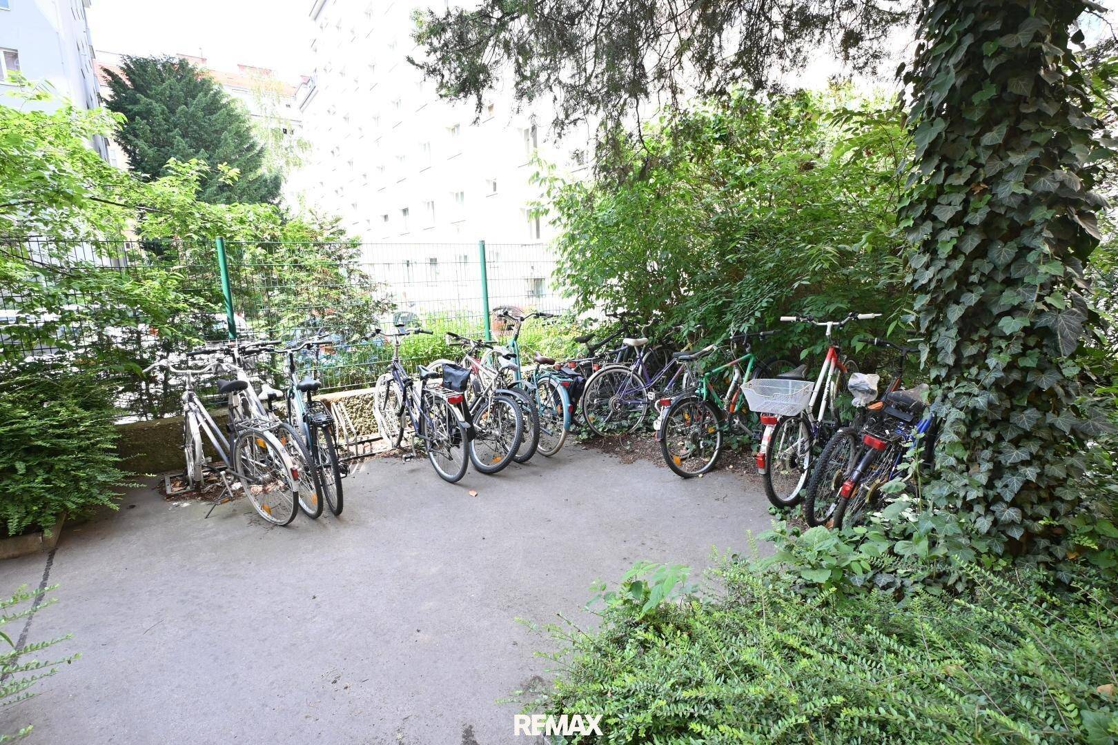 Fahrradabstellplatz im Freien, umgeben von Bäumen und Sträuchern, bietet sichere Parkmöglichkeiten.