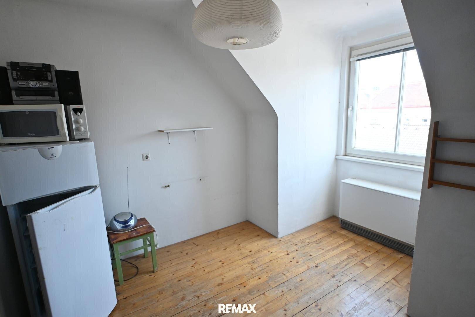 Leerer Raum mit Holzdielenboden, Dachschräge und Fenster, bietet Potenzial für verschiedene Nutzungen.
