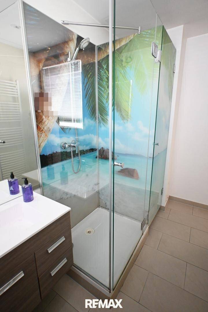 Duschkabine im Badezimmer mit tropischem Wandmotiv, bietet eine erfrischende Atmosphäre.