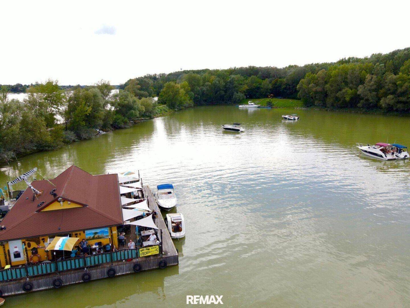 Luftaufnahme des schwimmenden Gebäudes mit Gästen auf der Terrasse und mehreren Booten auf dem See.