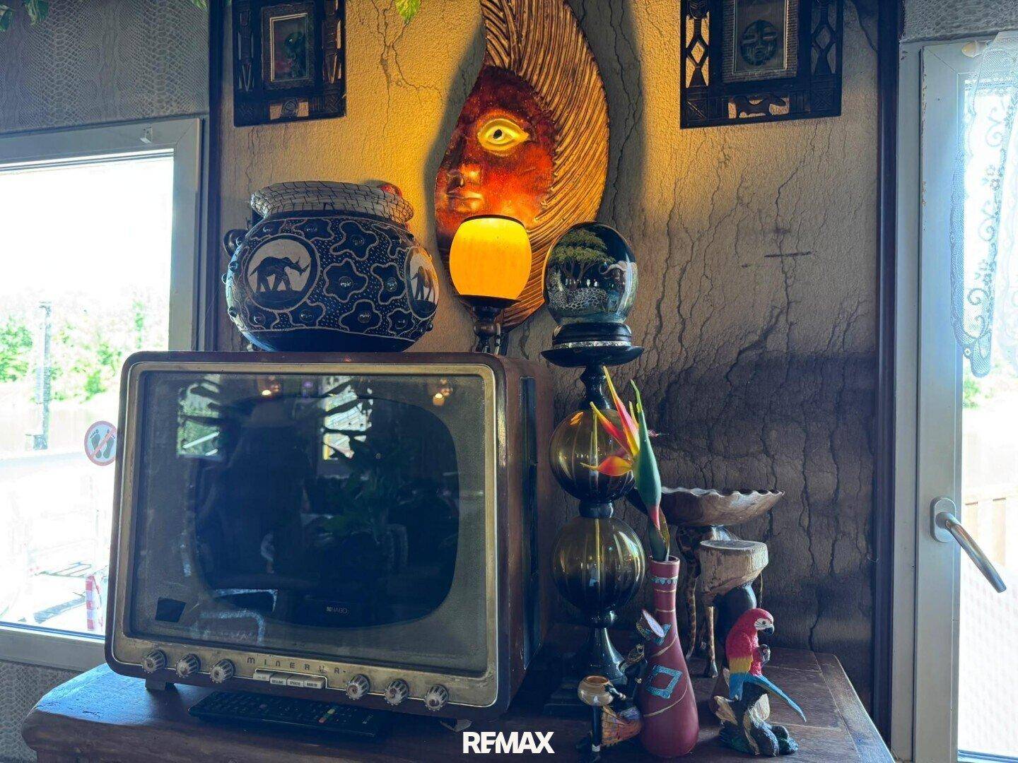 Detailaufnahme einer Vintage-Fernsehers und exotischer Dekorationselemente auf einem Holztisch.