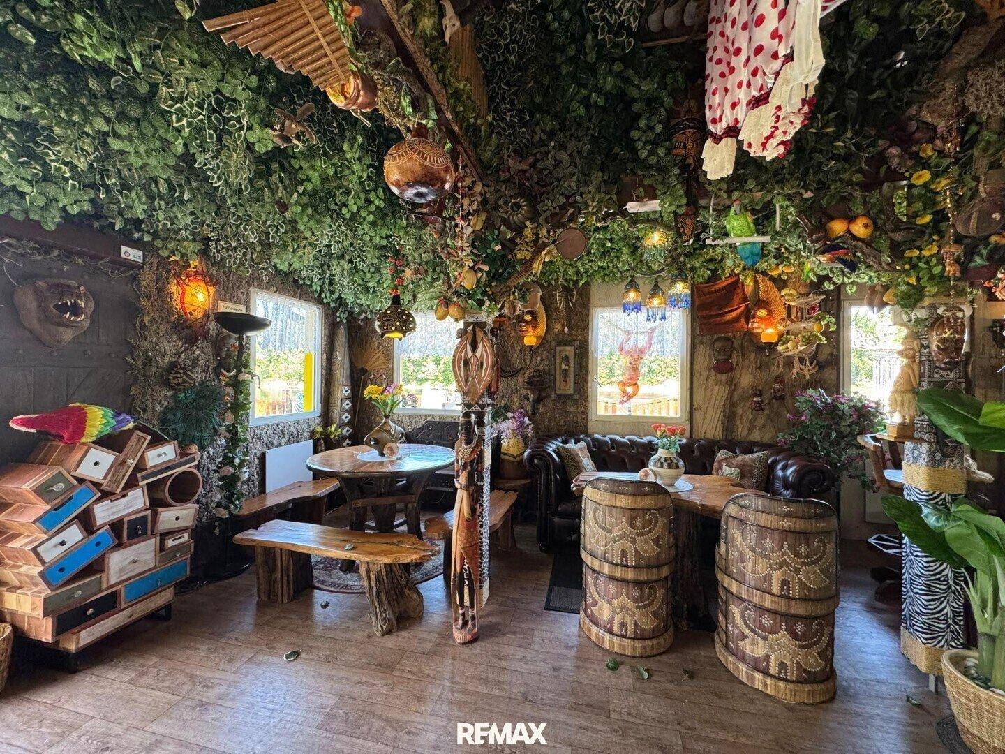 Ein exotisch gestalteter Innenraum eines Restaurants mit üppiger grüner Dekoration und rustikalen Holzmöbeln.