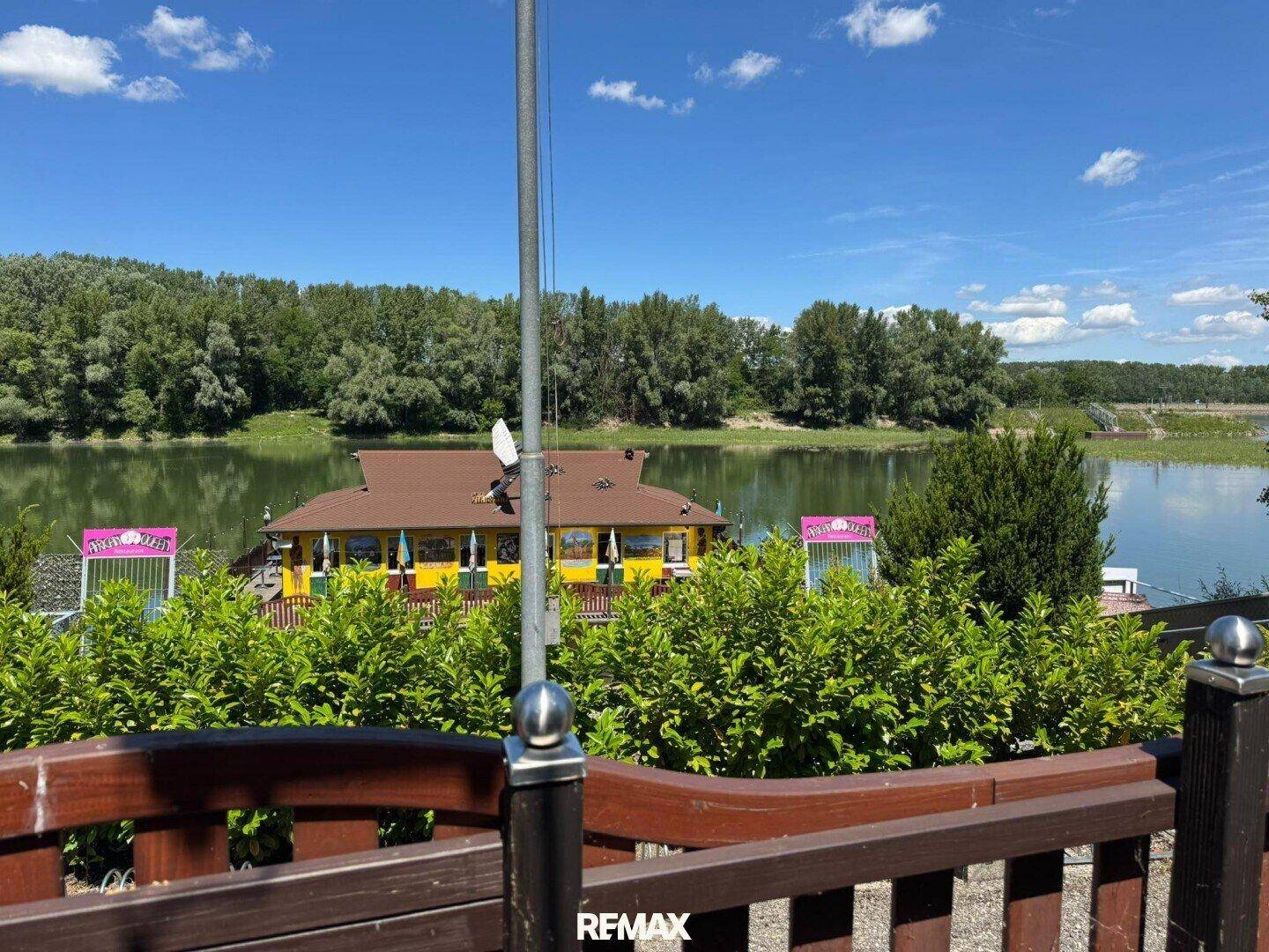 Blick auf das schwimmende Gebäude mit Restaurantbetrieb, umgeben von üppiger Natur und Wasser.