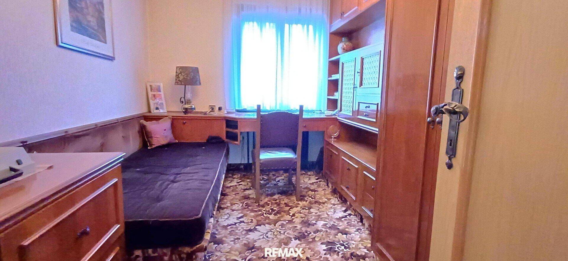 Gemütliches Schlafzimmer mit Holzelementen, Einzelbett und Schreibtisch.